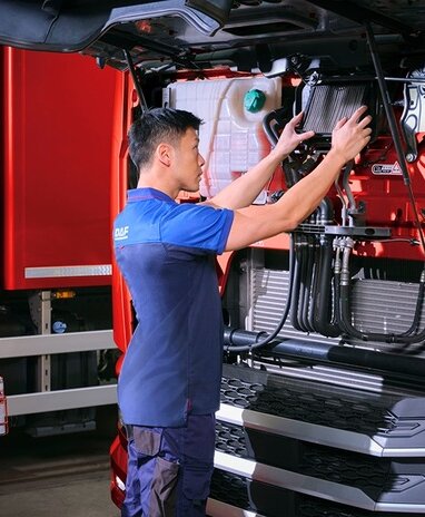 Ein Techniker überprüft einen LKW-Motor in einer Werkstatt.