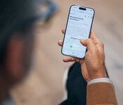 Person mit einem Smartphone, auf dem eine deutsche Webseite geöffnet ist.