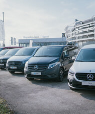 Reihe von Mercedes-Benz Fahrzeugen vor einem Mercedes-Benz Autohaus.