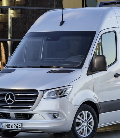 Ein weißer Mercedes-Benz Sprinter parkt vor einem modernen Glasgebäude.