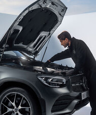 Ein Mechaniker von Pappas überprüft den Motor eines Mercedes-Benz mit offener Motorhaube.