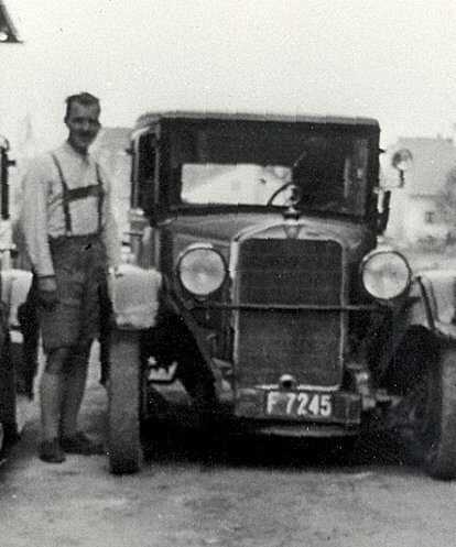 Drei Oldtimer mit Nummernschildern neben einer Person bei Pappas