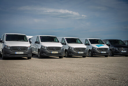 Mehrere weiße Mercedes-Benz Transporter parken in einer Reihe.