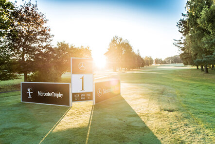 Golfplatz mit Mercedes-Benz-Banner bei Sonnenaufgang, Startpunkt Loch 1.