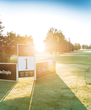 Golfplatz mit Mercedes-Benz-Banner bei Sonnenaufgang, Startpunkt Loch 1.
