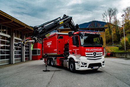 Feuerwehrfahrzeug mit Kranarm vor einer Feuerwache in bergiger Kulisse. | © Rene Oberhuemer