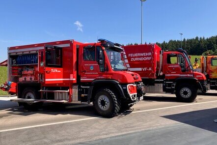 Zwei rote Unimog Feuerwehrfahrzeuge der Feuerwehr Zurndorf stehen nebeneinander.
