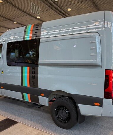 Grauer Camper-Van mit Streifen und 'Pappas' Logo auf Messe.
