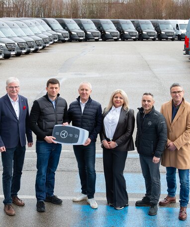 Übergabe von Mercedes-Benz Fahrzeugen an eine Gruppe von Personen.