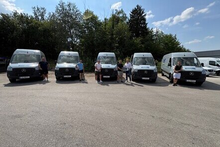 Fünf Personen posieren vor fünf neuen Mercedes-Benz Sprinter Kastenwagen.