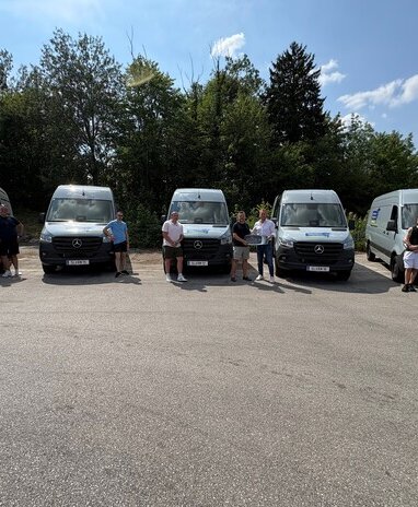 Fünf Personen posieren vor fünf neuen Mercedes-Benz Sprinter Kastenwagen.