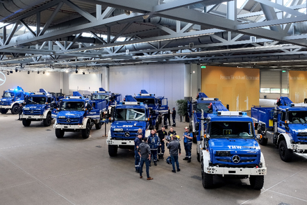 Mercedes-Benz Einsatzfahrzeuge bei einer Veranstaltung in einer großen Halle. Personen stehen um die Fahrzeuge herum. | © THW