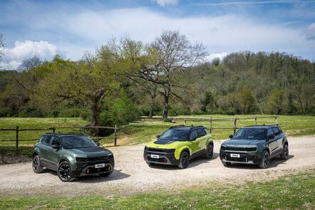 Drei Jeep-SUVs auf einem landschaftlichen Weg mit Bäumen im Hintergrund.