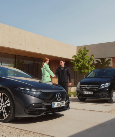 Ein Kunde begrüßt einen Mitarbeiter von Mercedes-Benz vor einem Gebäude. Ein Mercedes-Benz EQ Auto und ein Lieferwagen sind zu sehen.