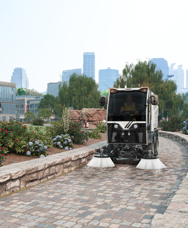 Bucher Municipal CityCat VR17e reinigt einen gepflasterten Parkweg.