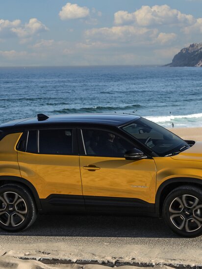 Gelber Jeep Avenger auf einer Küstenstraße mit Meerblick.