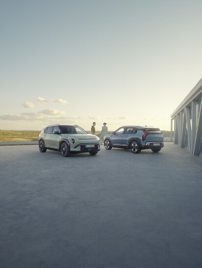 Zwei Kia EV3 Autos stehen auf einem Gelände neben einem modernen Gebäude im Sonnenuntergang. | © Kia Europe GmbH
