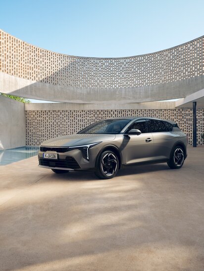 Ein silberner Kia K4 Hatchback steht in einem modernen, offenen Gebäude mit runden Formen und stilvollem Design.