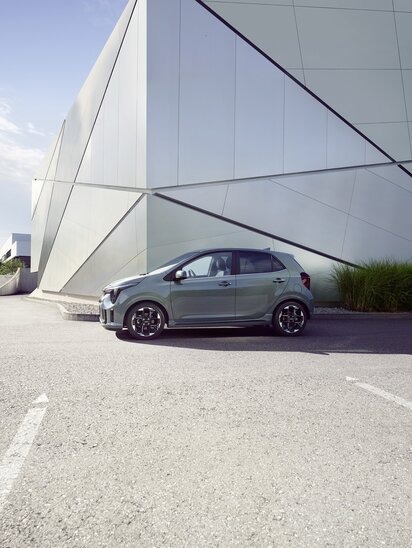 Ein grauer Kia Picanto vor einer geometrischen Gebäudefassade.