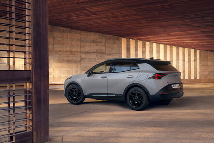 Grauer Kia Sportage SUV steht seitlich in einem architektonischen Innenhof aus Beton. | © Kia Österreich