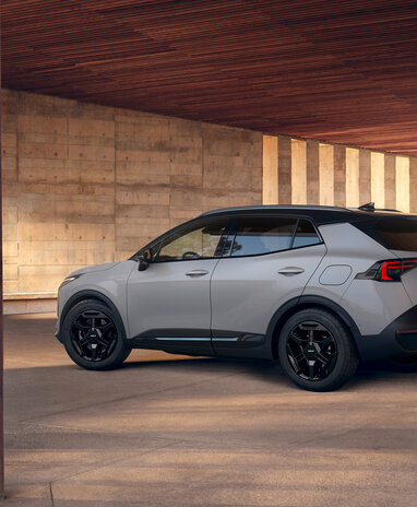 Grauer Kia Sportage SUV steht seitlich in einem architektonischen Innenhof aus Beton. | © Kia Österreich