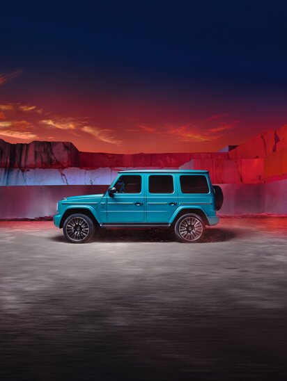 Türkise Mercedes-AMG G-Klasse vor einer Steinmauer bei Sonnenuntergang. | © Mercedes-Benz AG