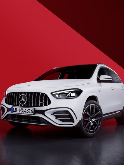 Ein weißer Mercedes-Benz AMG GLA auf spiegelnder Oberfläche vor rotem geometrischem Hintergrund. | © Mercedes-Benz AG