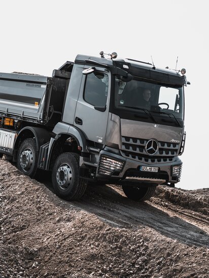Ein Mercedes-Benz Arocs fährt über ein hügeliges Gelände.