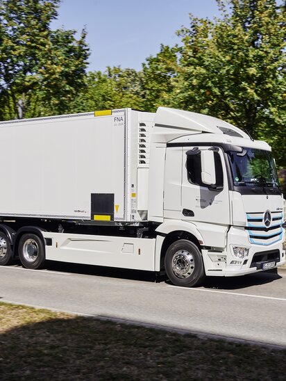 Ein weißer Mercedes-Benz eActros fährt auf einer Landstraße.