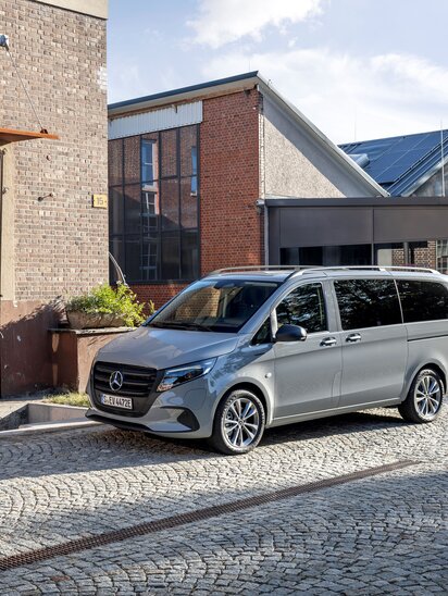 Ein Mercedes-Benz eVito Tourer parkt vor einem alten Fabrikgebäude auf einer gepflasterten Straße. | © Mercedes-Benz AG