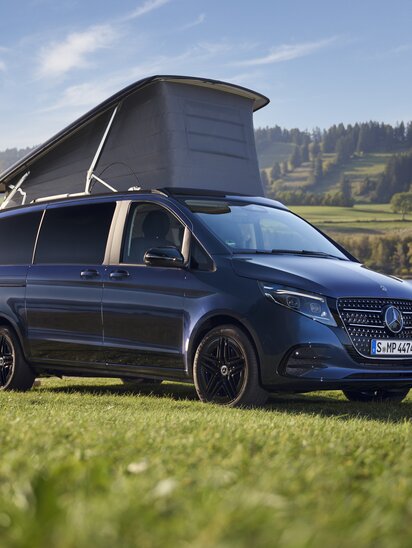 Ein blauer Mercedes-Benz Marco Polo mit geöffnetem Aufstelldach steht auf einer Wiese neben einem See. | © Mercedes-Benz AG