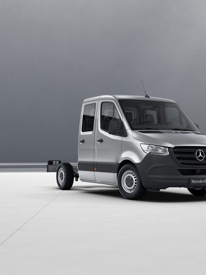 Silberner Mercedes-Benz Sprinter Fahrgestell mit Doppelkabine in leerem Raum.