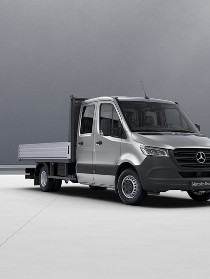 Silberner Mercedes-Benz Sprinter Pritsche mit Doppelkabine auf grauem Hintergrund.