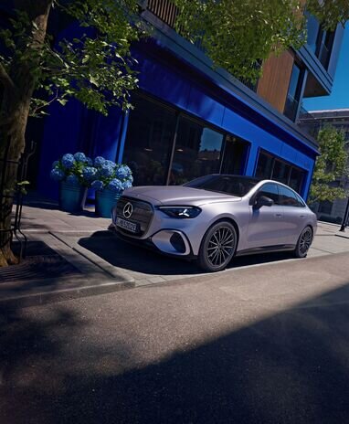Mercedes-Benz Auto parkt auf einer städtischen Straße vor einem blauen Gebäude, umgeben von Pflanzen. | © Mercedes-Benz AG