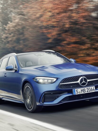 Blaues Mercedes-Benz C-Klasse T-Modell fährt auf einer Straße im Herbst.