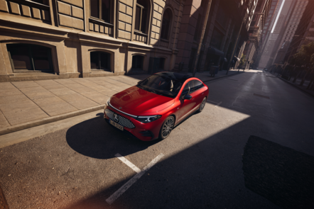 Roter Mercedes-Benz CLA mit EQ-Technologie auf einer leeren Stadtstraße bei Sonnenschein. | © Mercedes-Benz