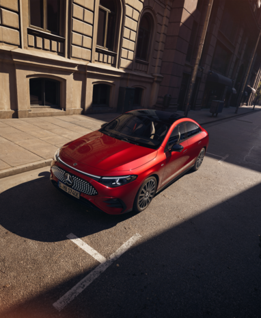 Roter Mercedes-Benz CLA mit EQ-Technologie auf einer leeren Stadtstraße bei Sonnenschein. | © Mercedes-Benz
