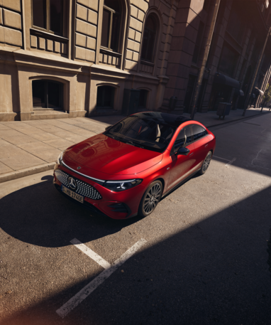 Roter Mercedes-Benz CLA mit EQ-Technologie auf einer leeren Stadtstraße bei Sonnenschein. | © Mercedes-Benz