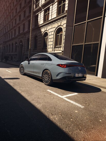 Mercedes-Benz CLA Limousine parkt in einer sonnigen Straßenszene einer Stadt.