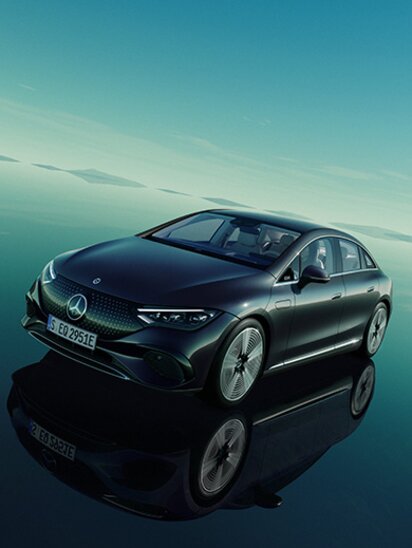 Schwarzer Mercedes-Benz EQE steht auf spiegelndem Boden unter blauem Himmel.