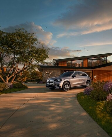 Ein silberner Mercedes-Benz GLC elektrisch steht vor einem modernen Haus mit Garten. | © Mercedes-Benz AG