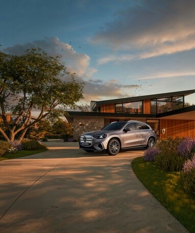 Ein silberner Mercedes-Benz GLC elektrisch steht vor einem modernen Haus mit Garten. | © Mercedes-Benz AG