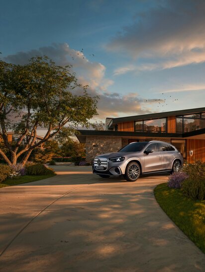 Ein silberner Mercedes-Benz GLC elektrisch steht vor einem modernen Haus mit Garten. | © Mercedes-Benz AG