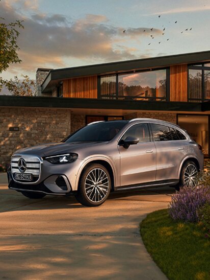 Ein Mercedes-Benz GLC elektrisch steht vor einem modernen Haus bei Sonnenuntergang.